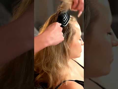 Lea gently lifts strands of the Client's hair, adjusting the weight with practiced ease as warm oil