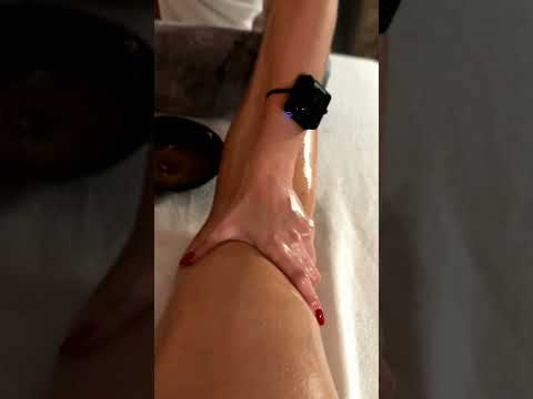 Watch as Mira smooths warm oil over the leg, her practiced strokes melting tension from calf to ankl